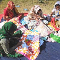 Group Members Doing Needle Work On Bed Cover
